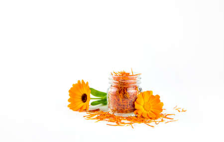 Dried Calendula officinalis the pot marigold, ruddles, common marigold or Scotch marigold, 
plant blossom petals in transparent clear glass jar with fresh blossoms isolated on white background.の写真素材