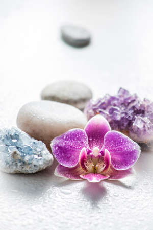 One pink orchid blossom with zen stones and amethyst cluster and blue cluster crystal on light...