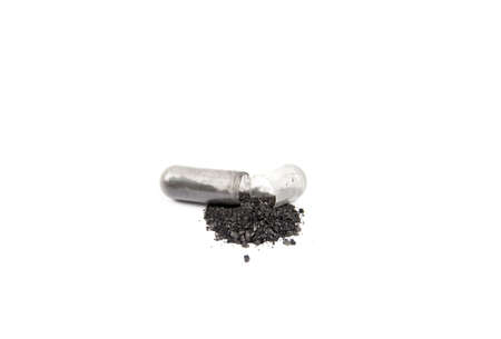 Opened activated charcoal capsule also known as activated carbon as medical drug isolated on white. Copy space.の写真素材