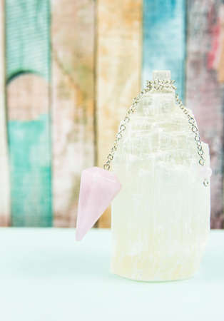 Using crystal Selenite tower for loading rose quartz pendulum, light blue table and pastel color...