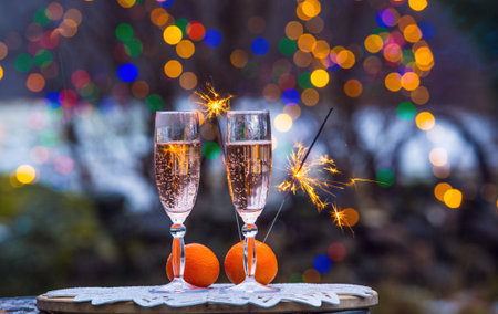 Celebrate New Years eve in home garden outdoors in winter, snowy evening, sparklers sparkle, copy space two flute glasses with champagne.の写真素材