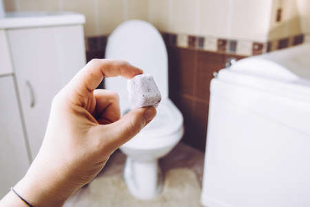 DIY toilet fizzie bomb for cleaning home toilet bowl. Selective focus on woman hand, holding homemade natural cleaning pod tablet. Green sustainable lifestyle concept.の写真素材