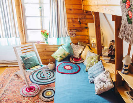 Maximalist maximalist home concept. Holiday home cabin bedroom with natural wooden board walls and ceiling and lot of different color details.の写真素材