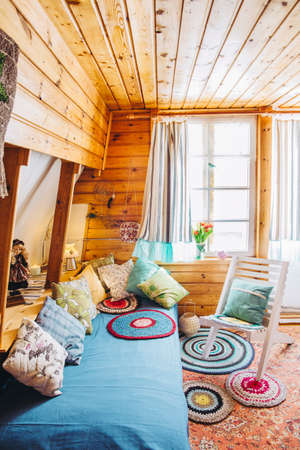 Maximalist maximalist home concept. Holiday home cabin bedroom with natural wooden board walls and ceiling and lot of different color details.の写真素材