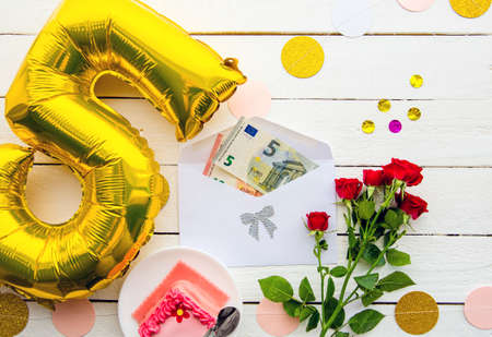 Euro money as birthday gift concept. Euro bank notes sticking out of envelope, decorated with balloon, cake and flowers.の写真素材