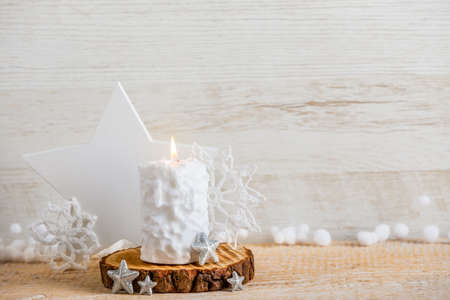 Vintage Nordic style minimalist Christmas background with a lot of copy space. Selective focus on snow ball pattern white candle burning, star shape decorations for decoration on wood background.の写真素材