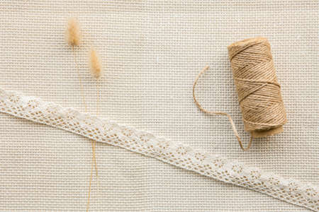 Minimal cotton cloth background with lace, cotton string roll and dry Lagurus ovatus hare's-tail straws or bunnytail. Lot of copy space, above view.の写真素材
