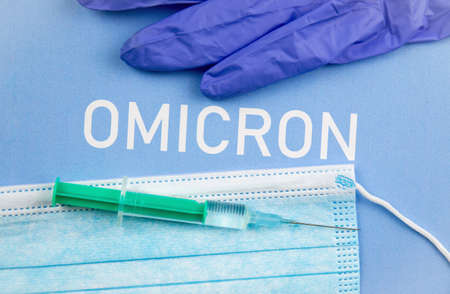 New Coronavirus Covid-19 mutation Omicron concept. Medical mask, syringe and text with letters Omicron.の写真素材