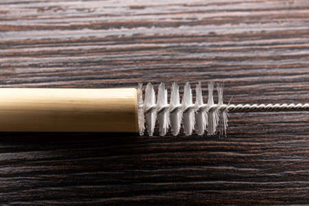 Close up view of using drinking straw cleaner brush to clean reusable bamboo drinking straw, indoors at home.の写真素材
