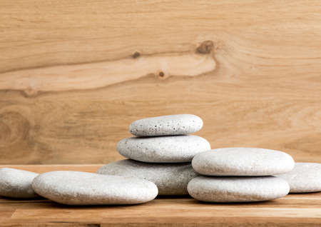 Minimalist beauty products background concept. Gray color flat sea stones stacked like an pedestal lot of copy space on oak wood background.の写真素材