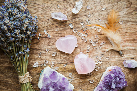 Above view of two polished pink color rose quartz crystals on wood tray in home. Attract love, healing heart chakra concept. Bouquet of dried lavender, feathers, stone chips for decoration.の写真素材
