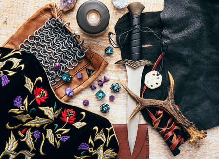 Fantasy role play board game still life concept. Background decorated with various character objects tools. Dagger, chain mail, amulet, clothing, dice set: D10, D20, D12, D6, D8.の写真素材