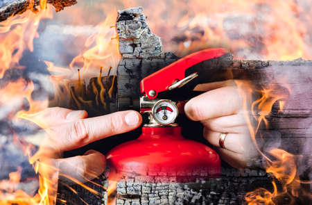 Close up view of man worker showing red fire extinguisher and controlling it. Maintenance service...