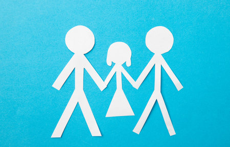 Same sex couple adoption concept. Paper dolls two fathers holding hands of offspring on blue background.の写真素材