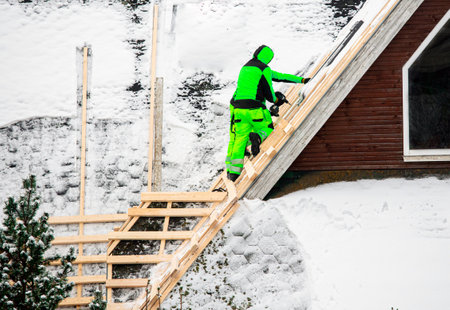 Workers reroofing or do an overlay for old roof. Building new tilted roof over an old one without removing it. Workers install wood board grid for new roof in the winter to domestiの写真素材