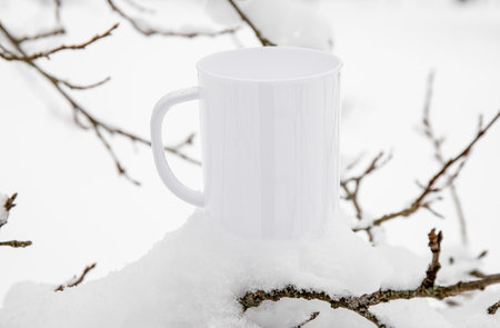 White blank coffee mug mock up template. Cozy seasonal products advertisement background. Single cup on snowy Scandinavian winter nature background. Room for text.の写真素材