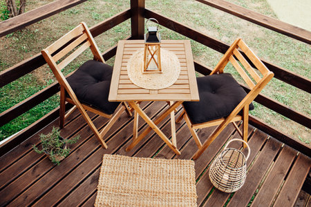 Modern boho style small wood balcony seating corner with wooden garden furniture, soft black...