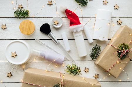 Flat lay view of handmade beauty products for Christmas present concept. Various generic jars and bottles, decorated with party lights on white wood board background.の写真素材