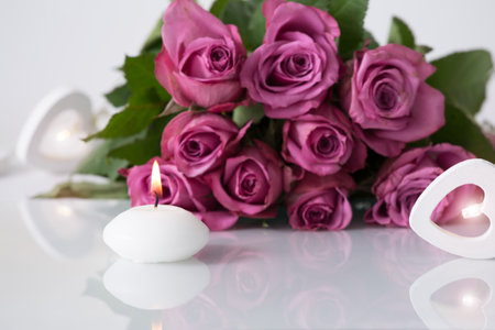 Beauty products background with wooden heart light, spa candle burning, bouquet of purple roses and nice reflection. Studio shot.の写真素材