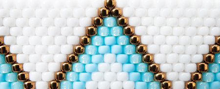 Macro shot of boho style beading backdrop. White, blue and bronze color beading pattern.