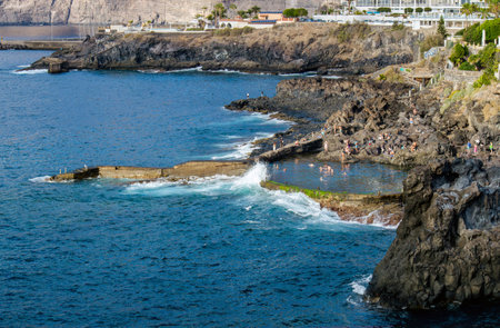 Los Gigantes, Santa Cruz de Tenerife, Spain-01FEB2025-People swimming and having fun in natural lava rock pool called Charco de Isla Cangrejo in Los Gigantes, Tenerife, Spain.の写真素材