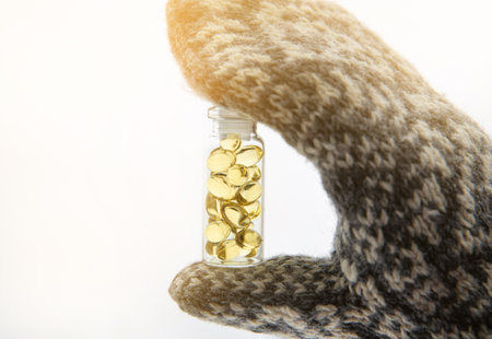 Vitamin D keeps you healthy while lack of sun in Nordic countries in the winter. Yellow soft shell D-vitamin capsules against white snow in glass jar.の写真素材