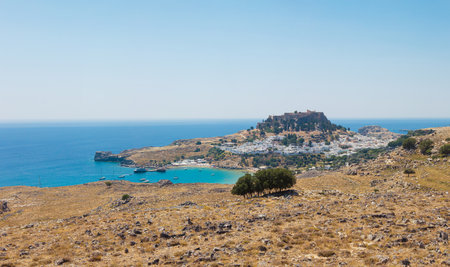 Lindos village on the island of Rhodes in Greece. Panoramic view over Lindos beach, village with whitewashed houses. The Lindos Acropolis and Temple of Athena Lindia.の写真素材
