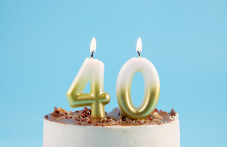 Number 40 birthday candle burning on cake. The fortieth birthday or anniversary celebration concept. Lot of copy space on blue background, studio shot.の写真素材