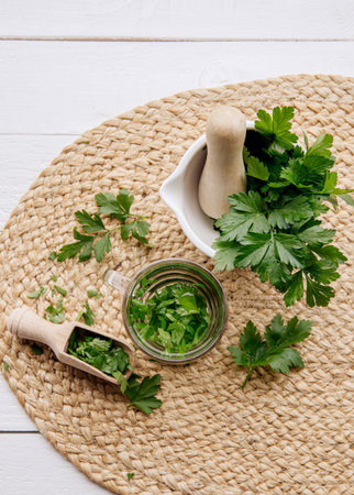 Above view of homemade herbal medicinal tea made from parsley. Green leaves in tea cup on white wood...