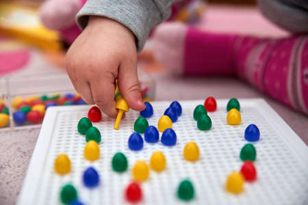toddler plays with colorful pinsの写真素材