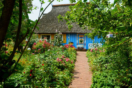 idyllic garden with blue thatched fisherman houseの写真素材