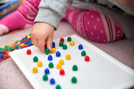 toddler plays with colorful pinsの写真素材