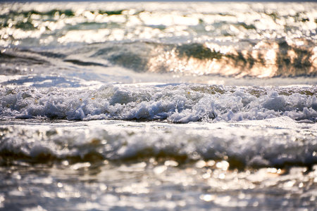 A brilliant green wave breaks near the shore, sparkling in the sunlight. Vivid water colors and...