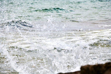 A brilliant green wave breaks near the shore, sparkling in the sunlight. Vivid water colors and...