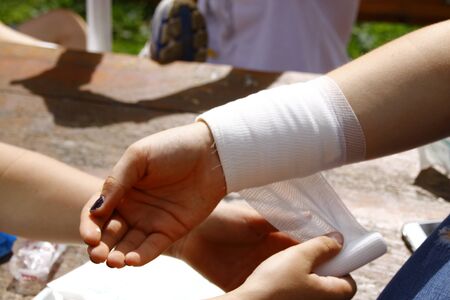 Applying a pressure bandage on a forearmの写真素材