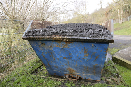 Waste container filled with sewage sludge. The container is overflowing, the mud could fall out in...