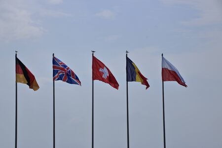 Waving flags flutter in front of a sky