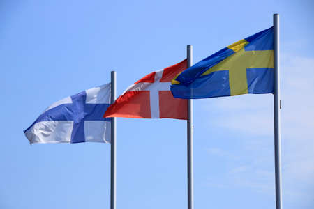 Flags blow in the wind against a blue sky
