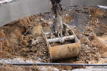 Excavator shovel digs into gravel ground