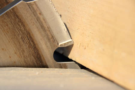A piece of lumber rests against the saw blade of a circular saw
