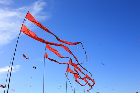 Red flags wave in the wind against a blue skyの写真素材