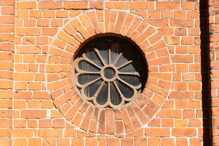 Round window with ornaments in a brick wallの写真素材
