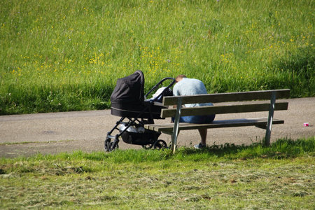 Person with a stroller sits on a park benchの写真素材