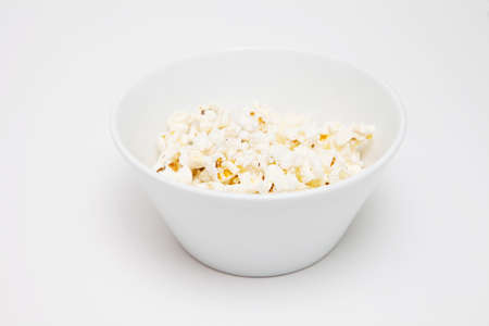 Popcorn in white bowl on the light background
