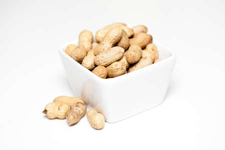 Peanuts in white bowl on the light background