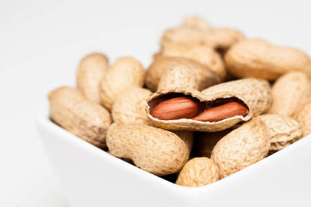 Peanuts in white bowl on the light background