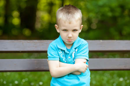 Sad unhappy blond boy in parkの写真素材
