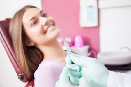 dentist hand holding a syringe, making a numb shot for woman patientの写真素材