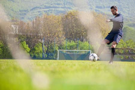 doing kick with ball on football stadium fieldの写真素材