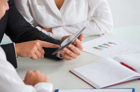 Image of people hand pointing at business document during discussion at meeting